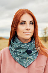 Junge Frau trägt Halstuch Damen aus Baumwolle grün, oliv, mint mit Pint wilder Eukalyptus. Dreieckstuch mit Knopf gefüttert mit Baumwollnicki und Knopf. stylisch, chic und wärmend.