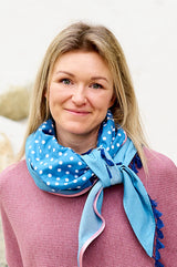 Frau trägt schickes Dreieckstuch aus hellem, dünnen Jeans mit weißen Punkten und verschiedenen Borten, wärmend, schützt vor Sonne und Wind, Himmelblau bringt dich zum strahlen, made with Love by wishproject, cool geknotet, wie ein Loop