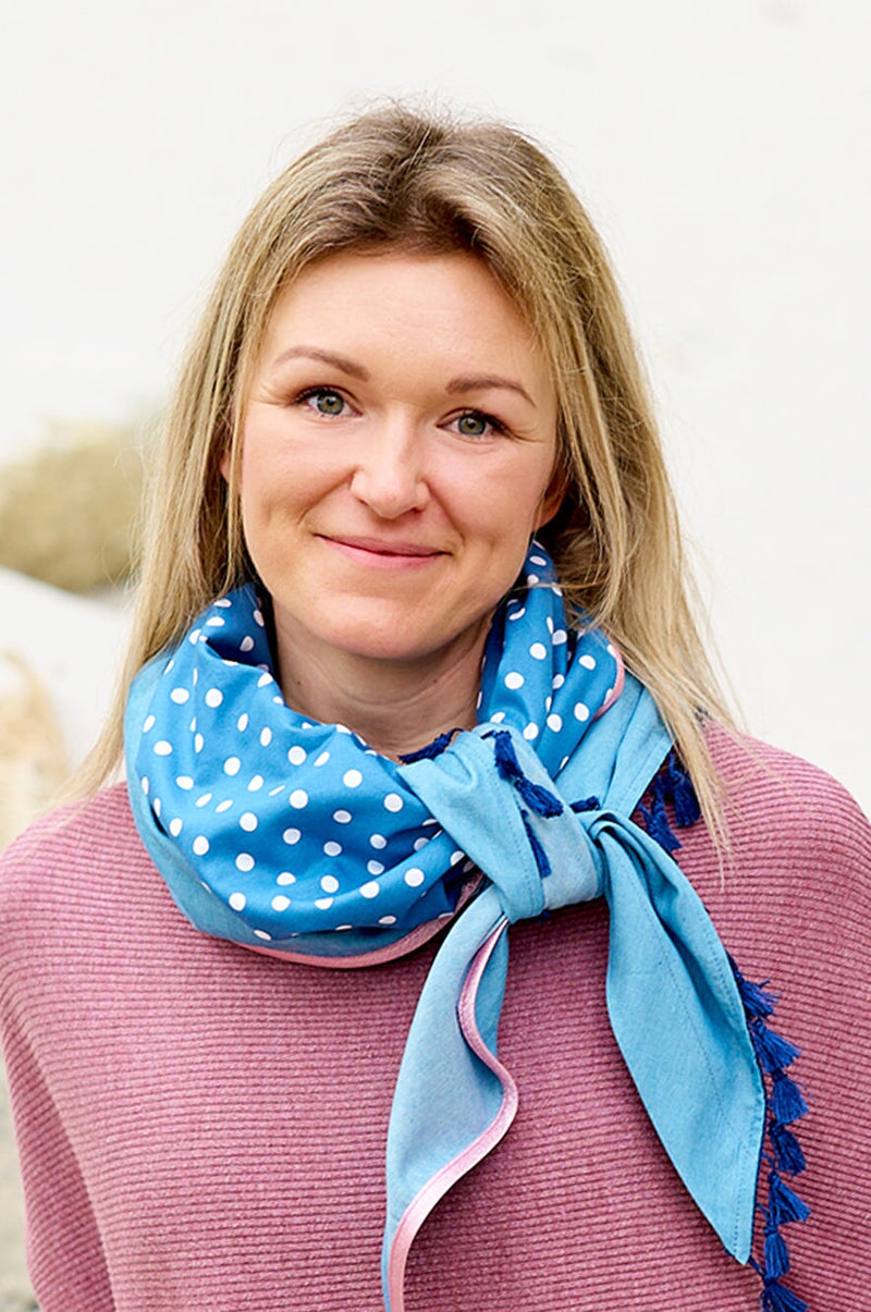 Frau trägt schickes Dreieckstuch aus hellem, dünnen Jeans mit weißen Punkten und verschiedenen Borten, wärmend, schützt vor Sonne und Wind, Himmelblau bringt dich zum strahlen, made with Love by wishproject, cool geknotet, wie ein Loop