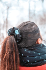 junge frau trägt scrunchie haargummi aus stoff schwarz und weiß mit pusteblumen 